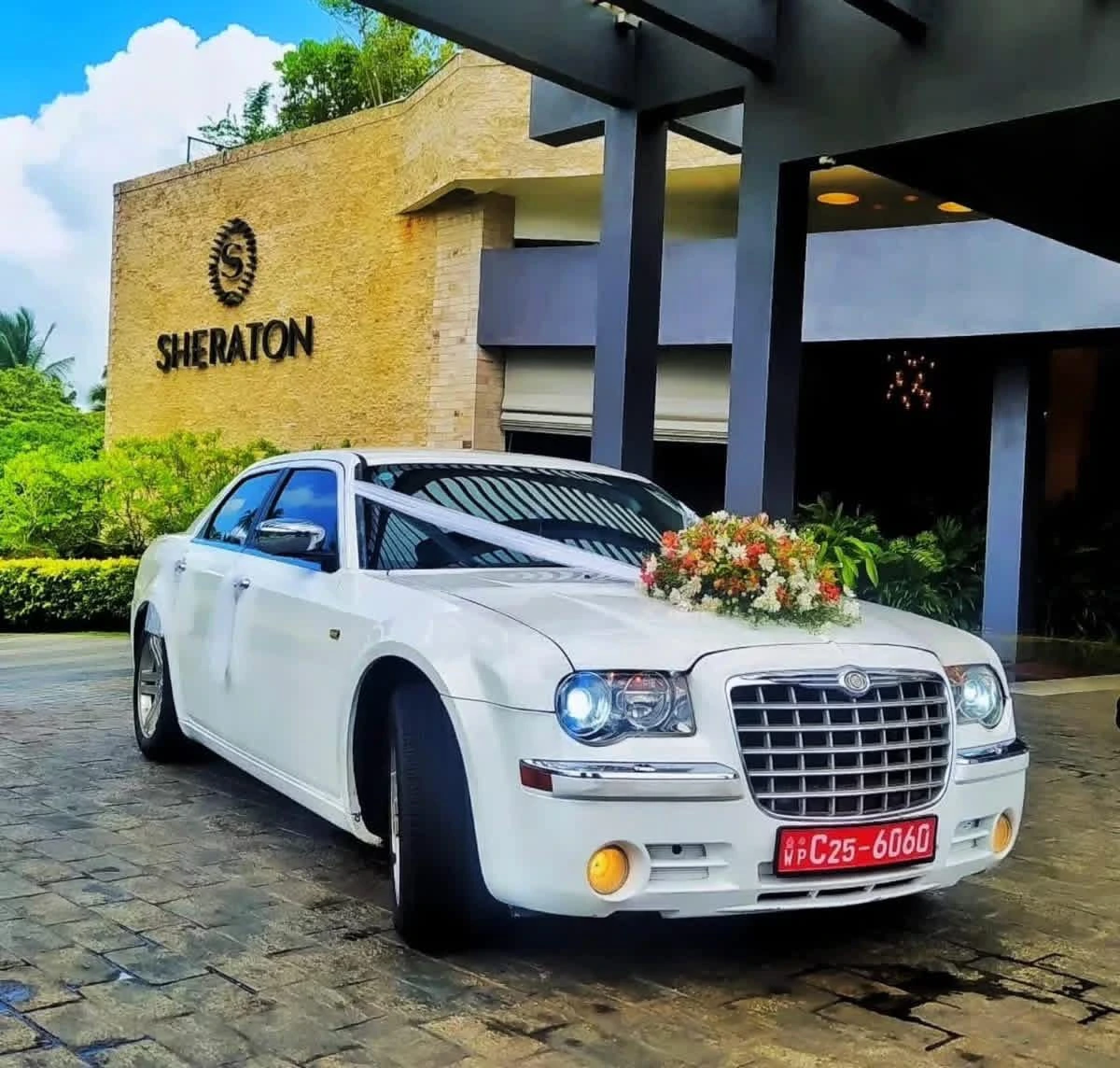 White luxury sedan with peach and pink floral hood decoration at a hotel entrance