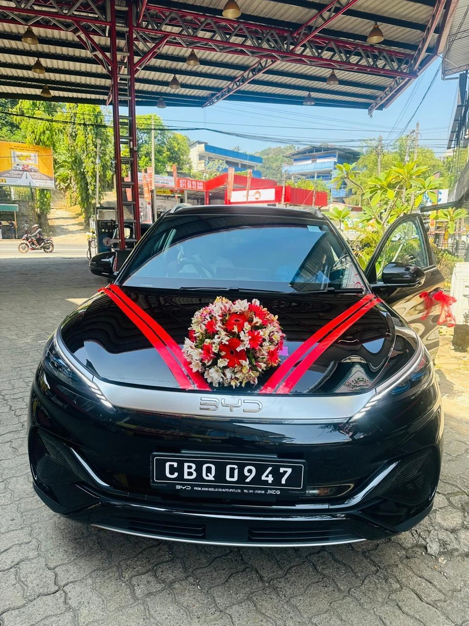 Black car with red and white floral hood bouquet and red ribbons